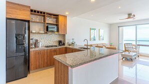 A modern kitchen with a built-in island, wooden cabinets, stainless steel appliances, and a large window overlooking the sea. - Cartagena Dreams (Cartagena)