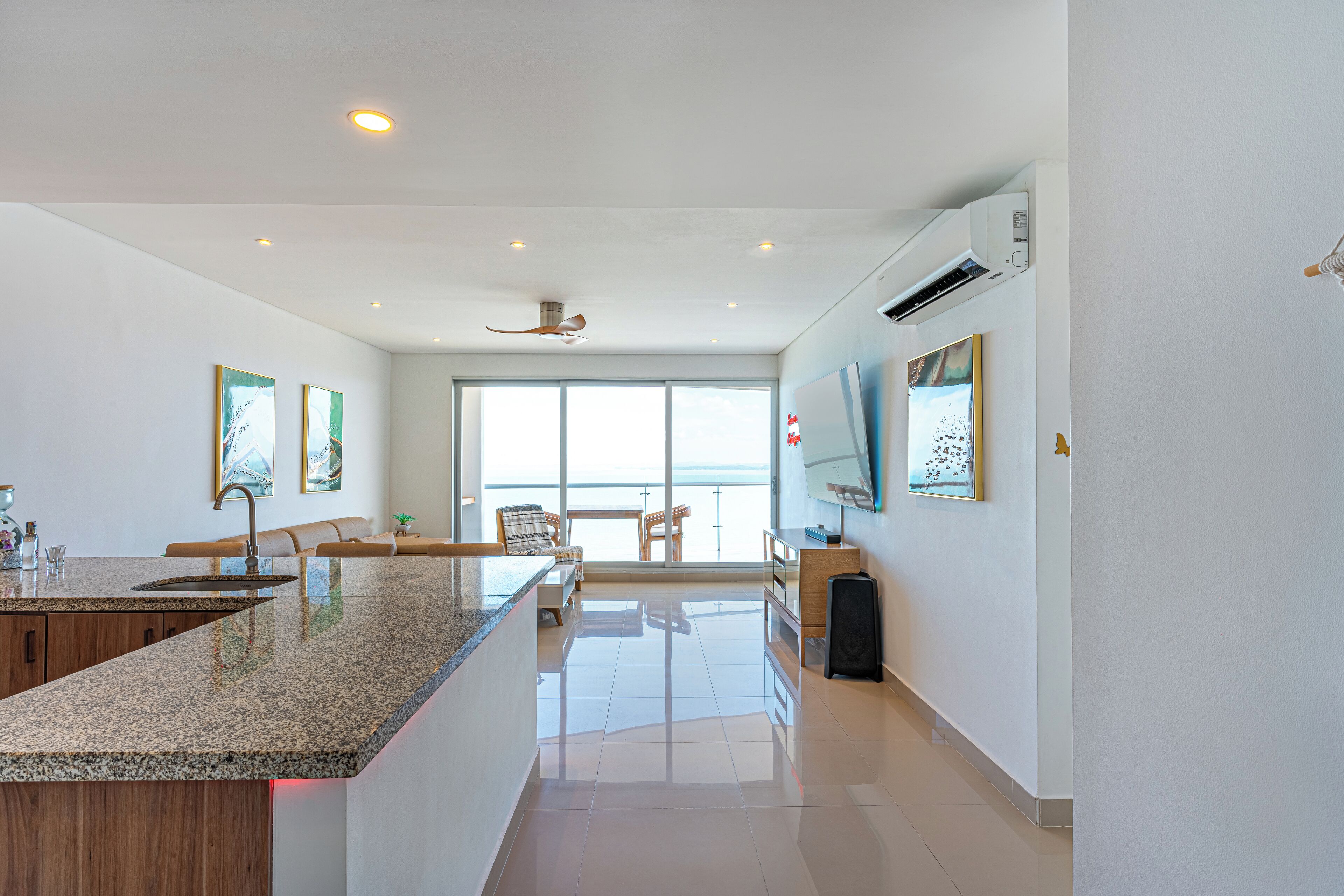 Una cocina moderna con encimera de granito, armarios de madera y un amplio ventanal con vistas al océano.