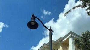 Eine Straßenlaterne vor einem mehrstöckigen Gebäude mit Balkonen und Palmen.