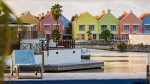 Une propriété située au bord de l’eau, avec des maisons aux couleurs vives, un quai et une piscine.