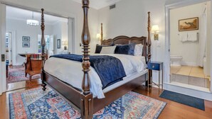 A spacious bedroom with a four-poster bed, a large window, and a view of the city.