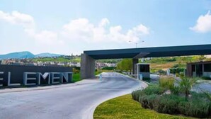 A modern building with a curved driveway leading to a covered entrance. - Luxury Apartment Fracc Element (San Agustín)
