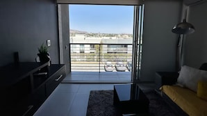 A modern living room with a large sliding glass door leading to a balcony. - Luxury Apartment Fracc Element (San Agustín)
