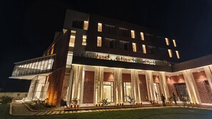 A modern building with multiple floors, large windows, and a well-lit entrance. - The Pearl Club Resort (Bolpur)