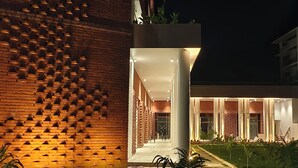 A modern building with a brick facade and a well-lit entrance area. - The Pearl Club Resort (Bolpur)