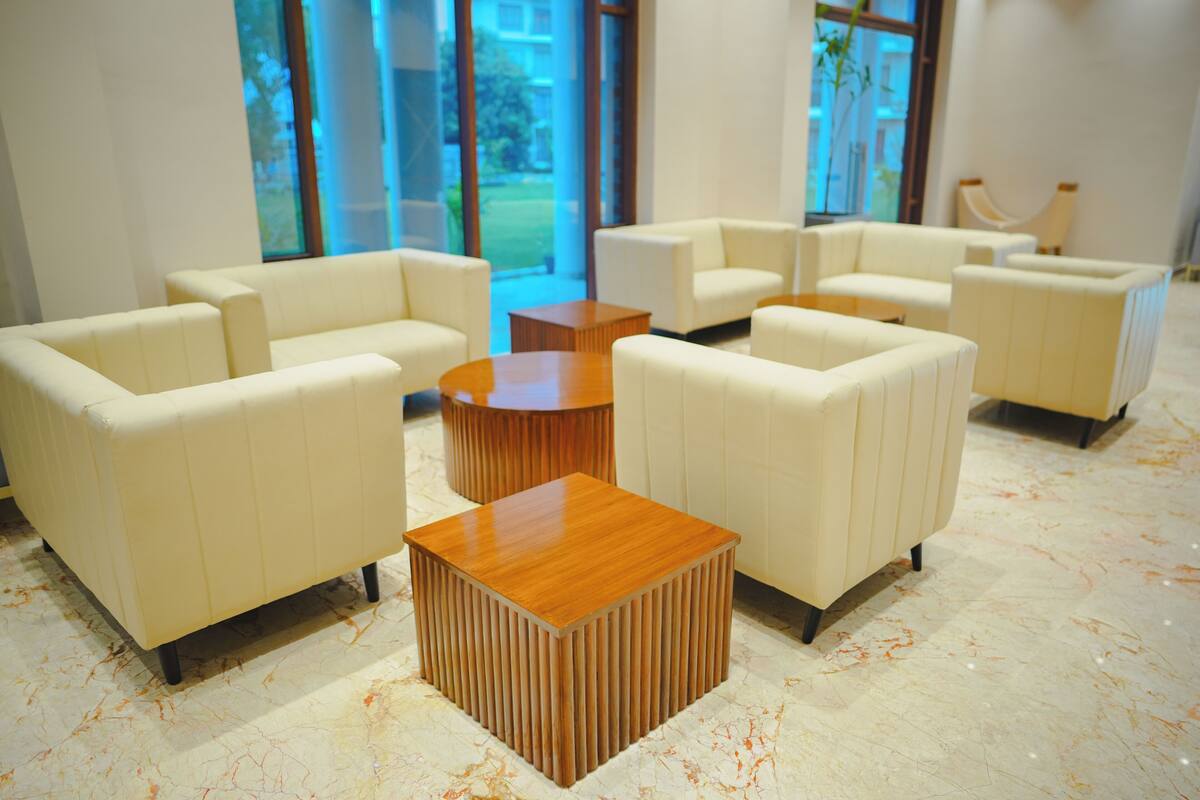 Un vestíbulo moderno con sofás de cuero blanco dispuestos alrededor de una mesa de centro de madera.