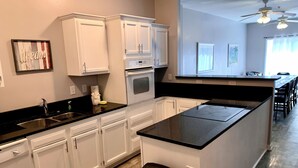 A modern kitchen with white cabinets, a black countertop, and a built-in oven.