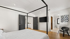 A modern bedroom with a four-poster bed, a flat-screen TV, and a minimalist decor. - Eastside Costa Mesa Home Walking Distance to Back Bay Newport Beach (Costa Mesa)