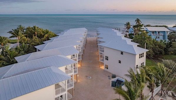 Um hotel à beira-mar com vários edifícios brancos, um pátio central e vista para o oceano.
