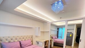 Quarto moderno com uma cama grande, mesa de cabeceira, espelho e guarda-roupa.