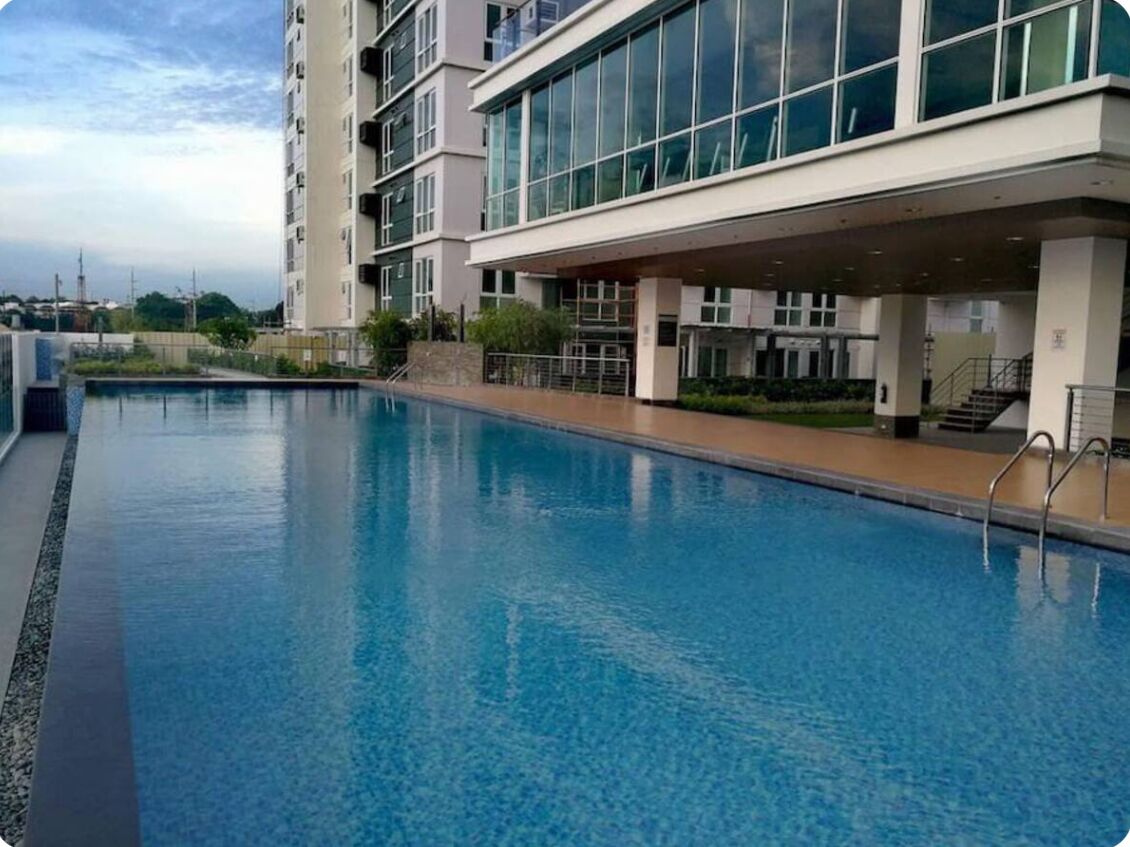 A swimming pool adjacent to a modern building with large windows and a covered walkway.