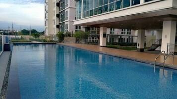 A swimming pool adjacent to a modern building with large windows and a covered walkway.