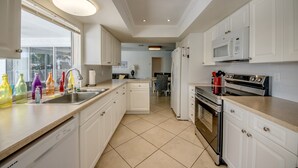 Una cocina moderna con armarios blancos, un lavamanos de acero inoxidable y un horno empotrado.