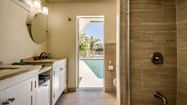 Un baño moderno con ducha, un espejo grande y vistas a una piscina.