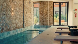 A swimming pool with stone walls and a view of the outdoors. - Laghetto Stilo Garden (Gramado)