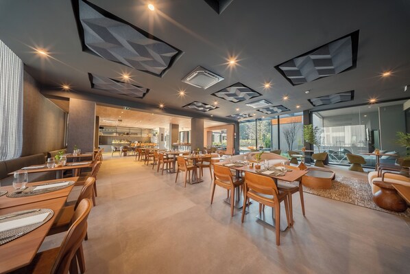 A spacious dining area with modern furniture and geometric ceiling design. - Laghetto Stilo Garden (Gramado)