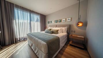 Un dormitorio moderno con una cama grande, una mesita de noche, una lámpara colgante y una ventana con cortinas.