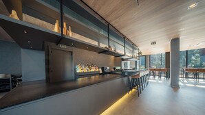 A modern bar area with a long counter, stools, and a variety of bottles. - Laghetto Stilo Garden (Gramado)