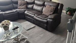 A living room with a sectional sofa, a glass coffee table, and a lamp. - Cozy 5-bdrm hm, Loaded Kitchen, w/ Patio 
Deck & Grill, WiFi in pleasant Norfolk (Norfolk)