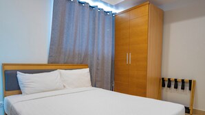 A neatly made bed with a wooden headboard, a large wardrobe, and a radiator.