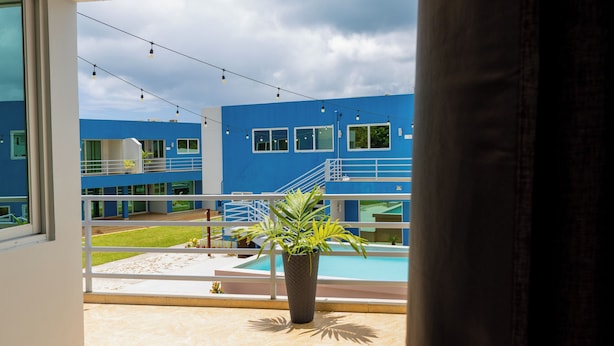 A balcony with a view of a swimming pool and a blue building in the background.