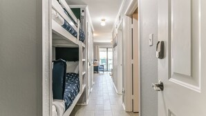 A narrow hallway with bunk beds on one side and a door on the other. - La CaSEAta - Beachfront Condo (Galveston)