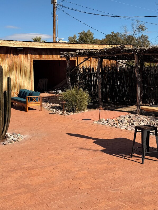 A rustic outdoor area with a wooden bench, a small table, and a cactus.