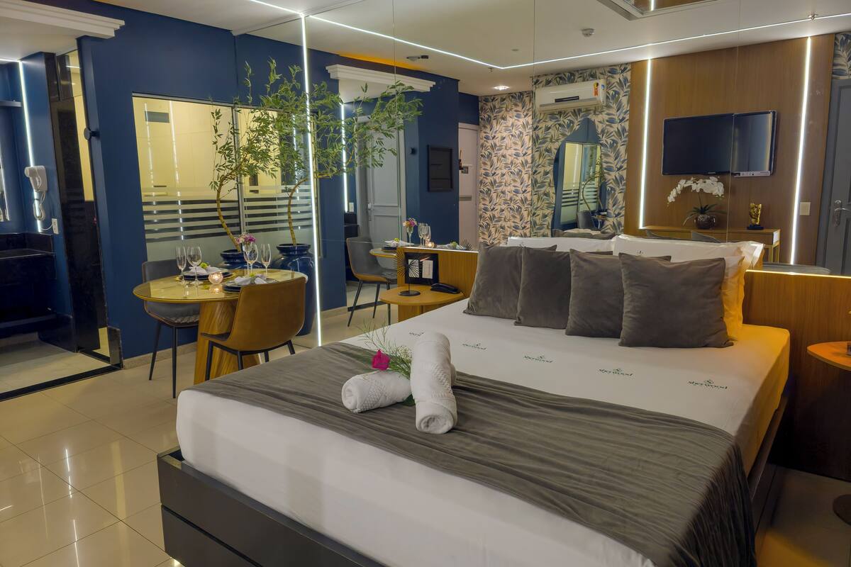Een moderne hotelkamer met een groot bed, een bureau met stoel, een zithoek en een aan de muur bevestigde televisie.
