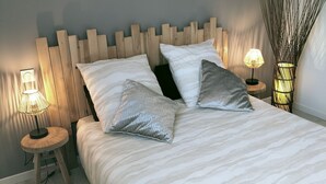 A neatly made bed with a wooden headboard, two bedside tables with lamps, and decorative wall art. - Quiet house (Bournainville-Faverolles)