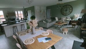 A spacious living area with a dining table, sofas, and a kitchen in the background. - Quiet house (Bournainville-Faverolles)