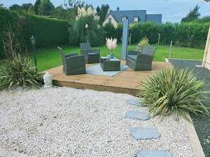 Un patio con mobiliario de mimbre, una estatua de Buda y una planta decorativa.