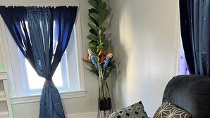 Een woonkamer met een grijze bank, een kamerbreed tapijt met dessin en decoratieve kussens.