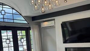 Una sala de estar moderna con un televisor grande, techo de vidrio y una planta en maceta.