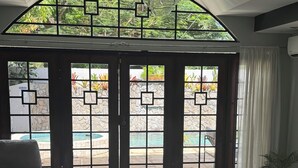 Una sala de estar moderna con un sofá seccional, una mesa de centro y vistas a una piscina a través de una puerta de cristal con un diseño geométrico.