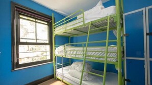Habitació amb lliteres, parets blaves i una finestra.