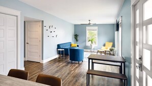 A modern living room with a blue sofa, a yellow armchair, a dining table, and a ceiling fan. - Pickwick Places 202 MSU/Rountree (Springfield)
