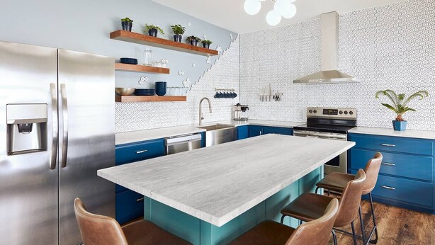 A modern kitchen with a central island, blue cabinets, and a stainless steel refrigerator. - Pickwick Places 201 MSU/Rountree (Springfield)