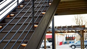 A staircase with metal railings and wooden steps leading to an outdoor area with picnic tables and cars parked nearby. - Pickwick Places 201 MSU/Rountree (Springfield)