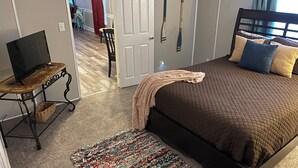 A bedroom with a bed, a television on a stand, a door, and a hallway. - 3/2 Sunken Treasure Spacious Home in college town of Troy with WiFi, AC (Troy)