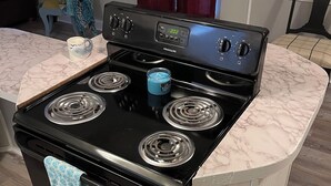 A kitchen with a black stove, a digital clock, and a marble countertop. - 3/2 Sunken Treasure Spacious Home in college town of Troy with WiFi, AC (Troy)