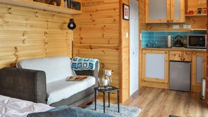 A cozy cabin interior with a wooden interior, a sofa, a small table, a kitchen area with a microwave, and a refrigerator. - Brockalee Farm Retreat (Bardon Mill, Near Hexham)
