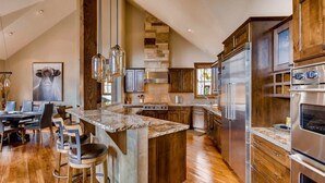 A modern kitchen with a central island, stainless steel appliances, and wooden cabinetry. - Breck_snowy_point_chalet (Breckenridge)