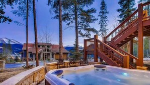 A hot tub with a wooden deck and stairs, surrounded by trees and a mountain view. - Breck_snowy_point_chalet (Breckenridge)