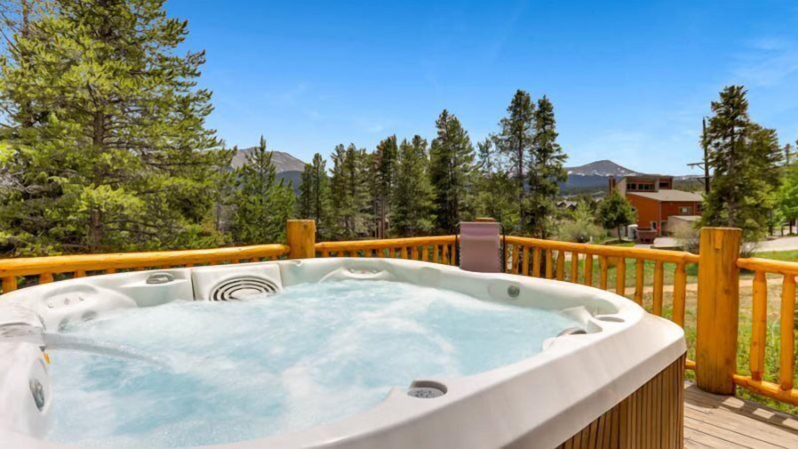 A hot tub on a wooden deck with a view of trees and a mountain in the background.