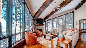 A spacious living room with large windows, a fireplace, and wooden flooring. - Breck_grand_vista_lodge (Breckenridge)
