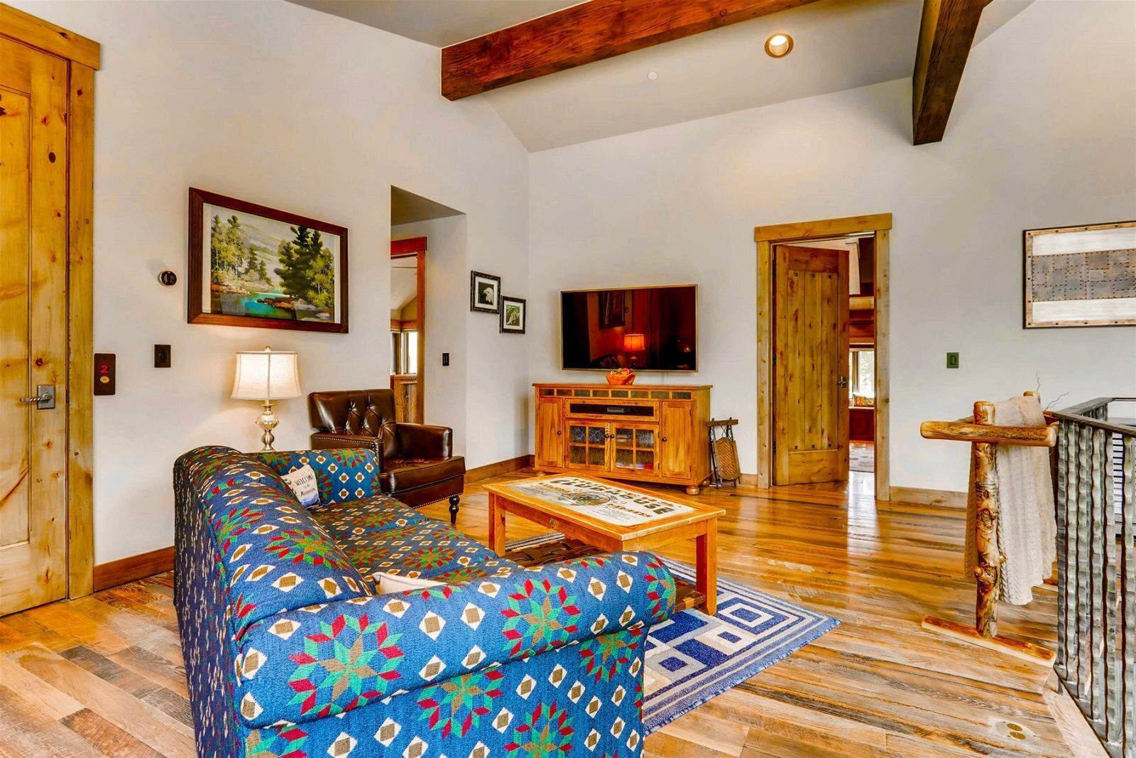 A cozy living room with a patterned sofa, a wooden cabinet, and a television.