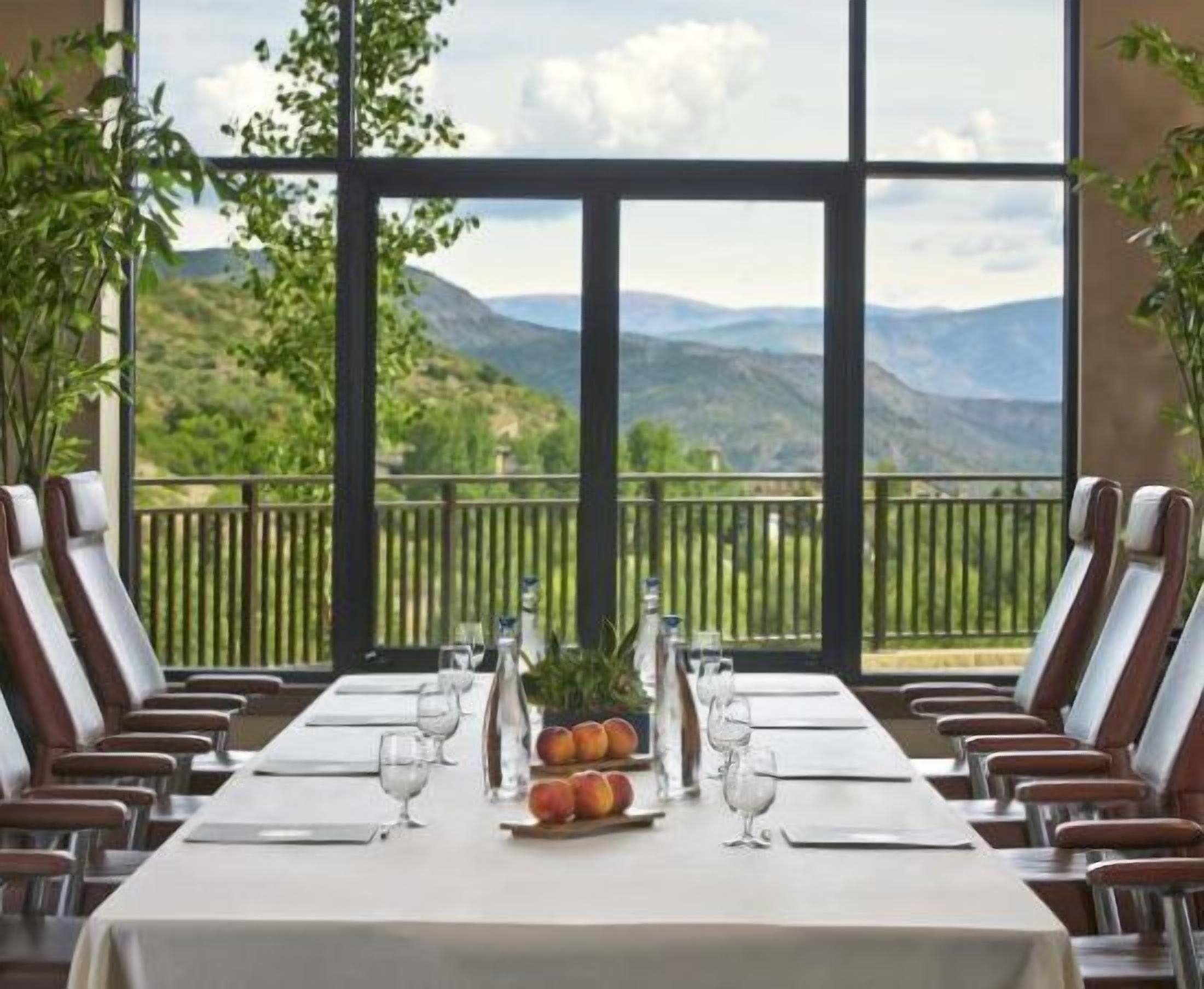 A dining table set for six with a mountain view through large windows.
