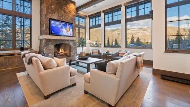 A spacious living room with a stone fireplace, large windows, and a comfortable seating area. - Vail_alpenzauber_lodge_5bd (Vail)