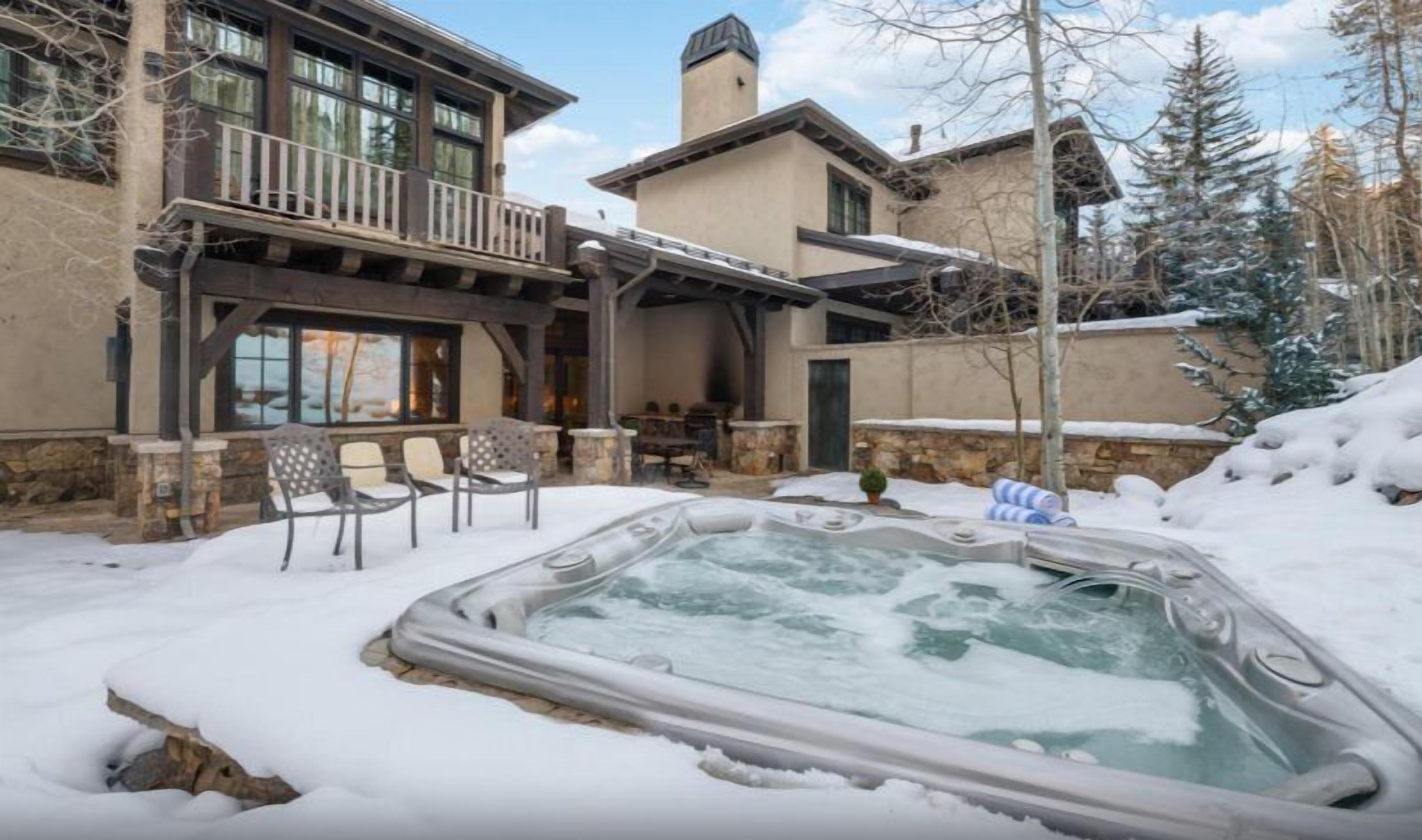 Un espace de détente avec un jacuzzi entouré de murs en pierre et une terrasse en bois.
