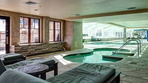 An indoor swimming pool area with lounge chairs, a seating area with a view of the pool, and a large window. - Crystal Peak 2 Bedroom Condo at Peak 7 (Breckenridge)
